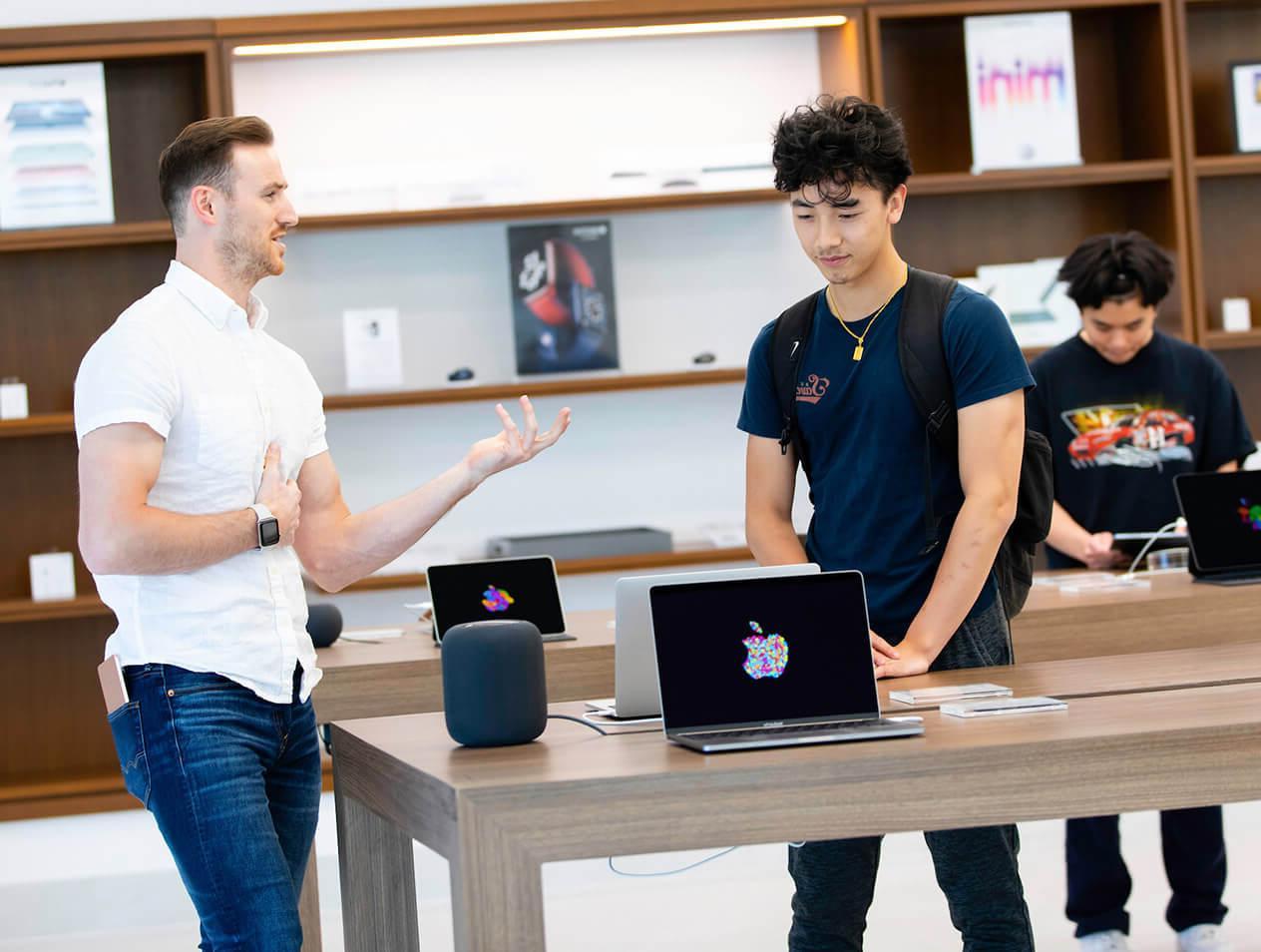 An iJay store employee explaining a laptop's features to a Creighton student